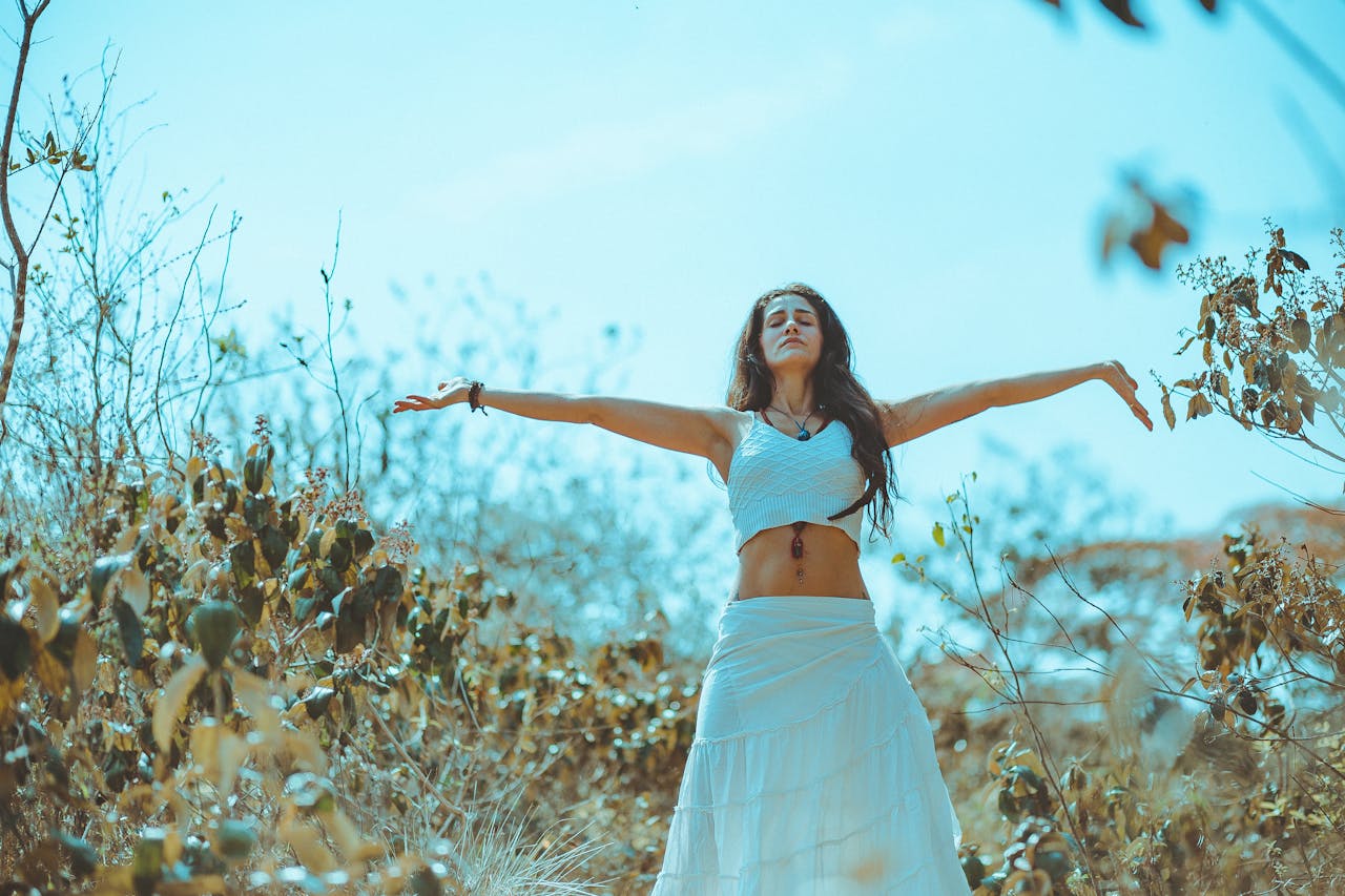 Home A woman in a white dress enjoying freedom and nature in a sunlit field.