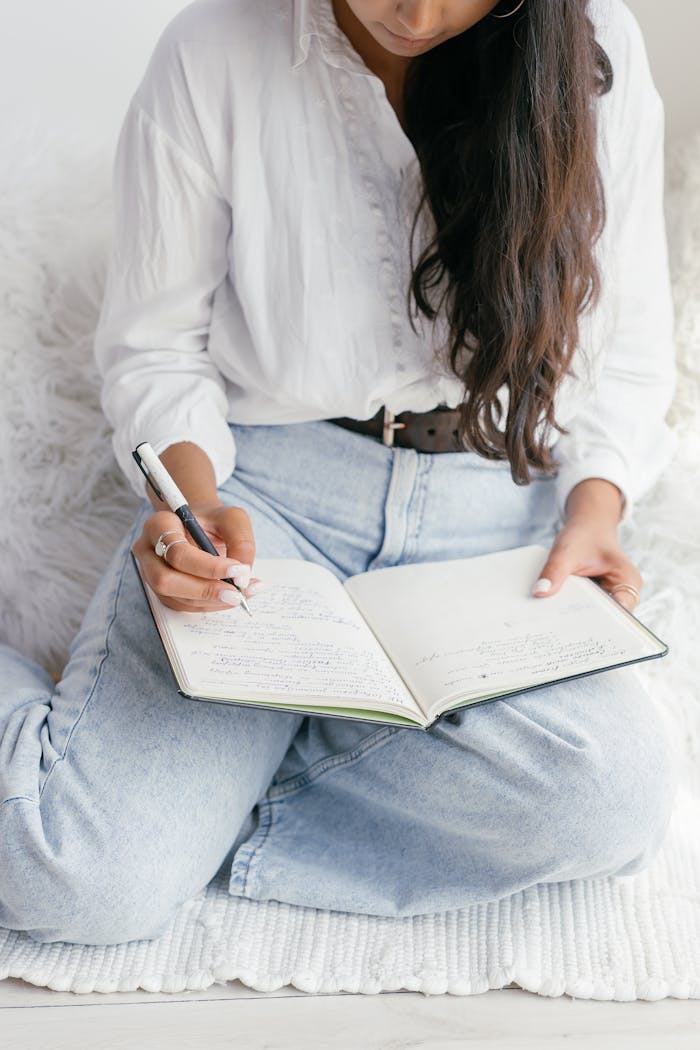 Offerings Young woman writing in a notebook indoors, reflecting on education and learning.